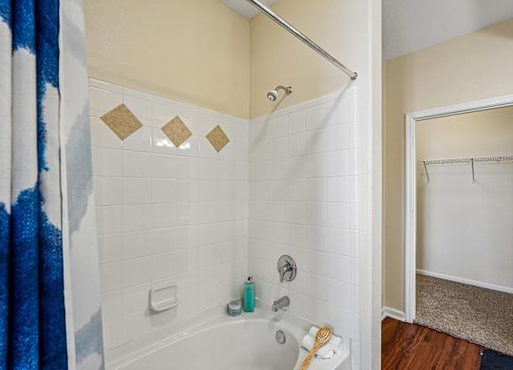 A bathroom with a white tub and a blue shower curtain.