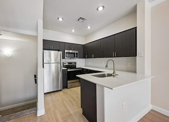 A kitchen with a white fridge and black cabinets.