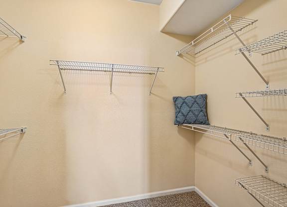 A walk-in closet with shelving and a pillow on the wall.