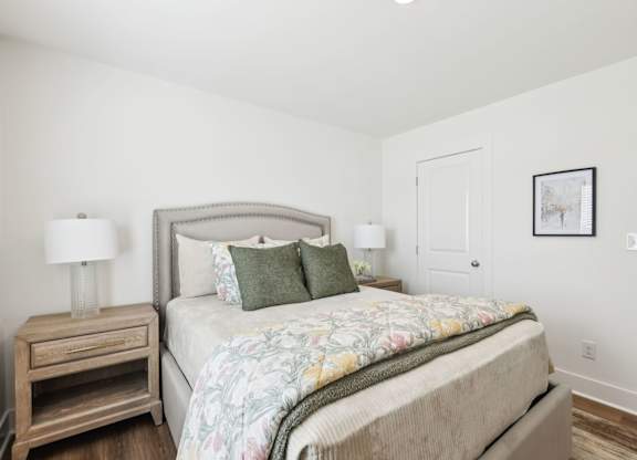 A bedroom with a large bed and a wooden nightstand.