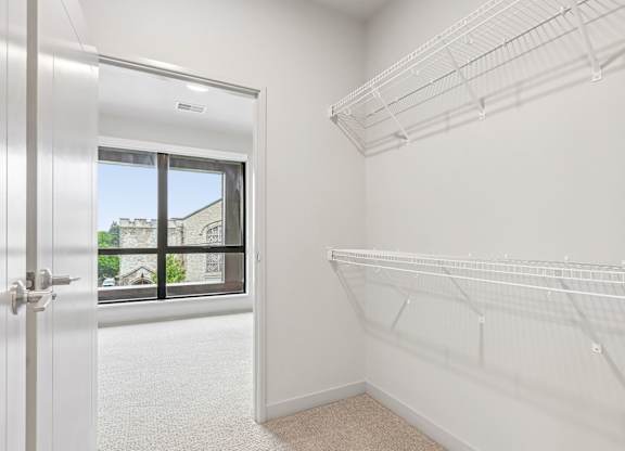 A white closet with shelves and a door leading to a balcony.