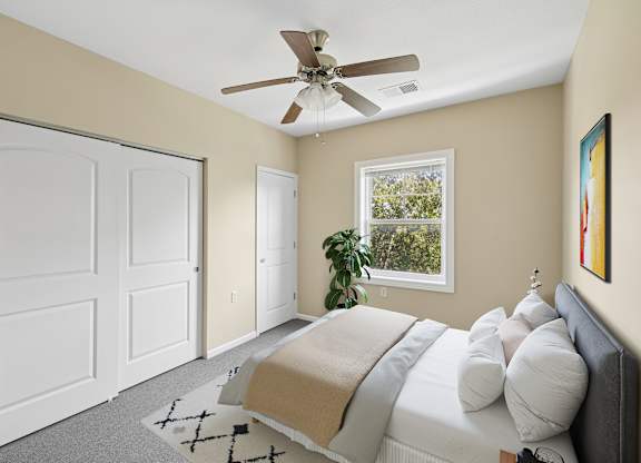 A bedroom with a bed, pillows, a ceiling fan, and a window.