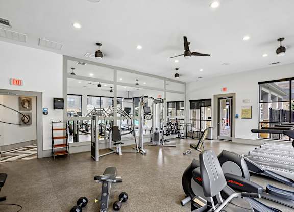 A gym with a variety of equipment including treadmills, weights, and exercise machines.