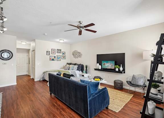 A living room with a blue couch and a ceiling fan.