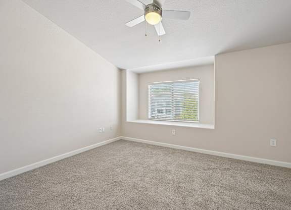 A room with a ceiling fan and a window with blinds.