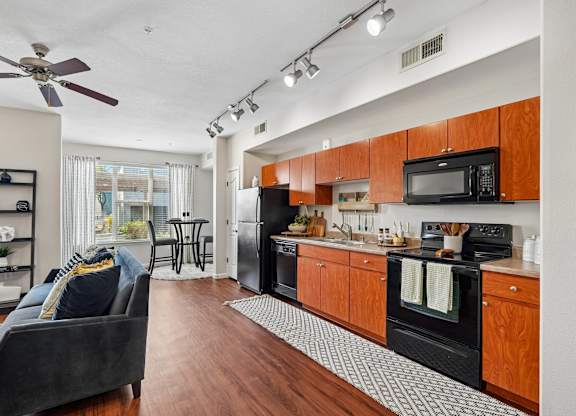 A modern kitchen with wooden cabinets and black appliances.