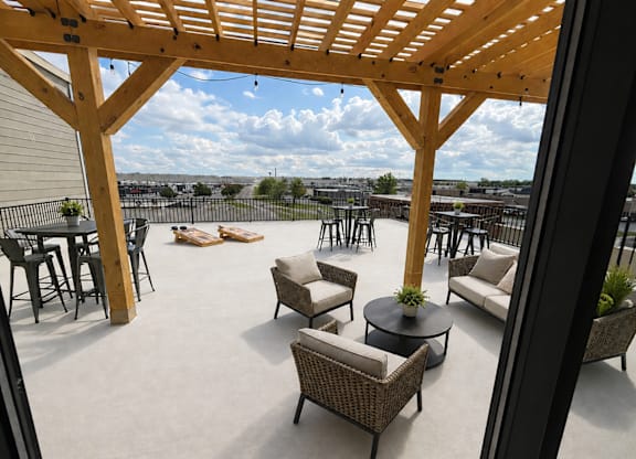 Kokomo, IN, Apartments with In-Unit Washer and Dryer - The Elwood Apartments - Rooftop Lounge With A Wooden Pergola, Lounge Seating, High Top Tables, Cornhole Boards, And Open Sky Views.