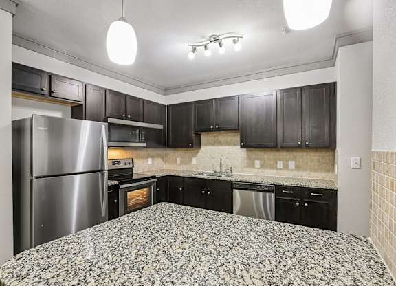 A kitchen with black cabinets and a stainless steel refrigerator.