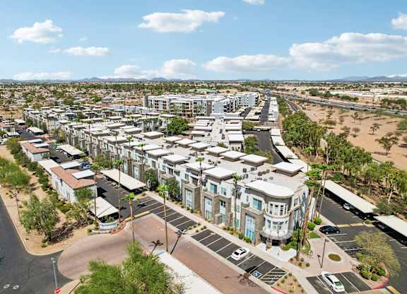 A large, modern residential complex with a parking lot in front.