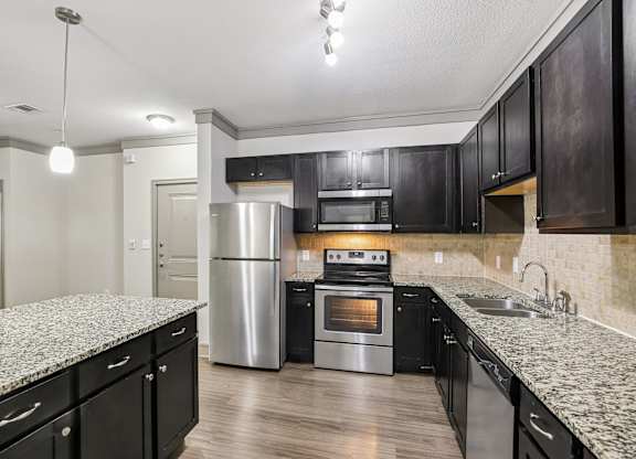 A kitchen with black cabinets and a granite countertop.