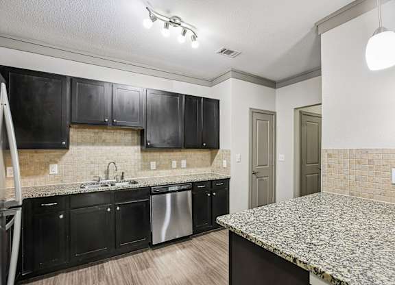 A kitchen with black cabinets and a granite countertop.