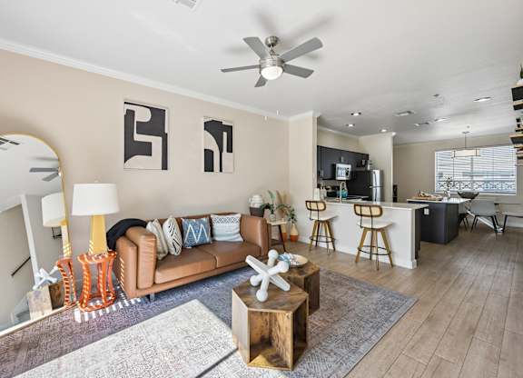 A living room with a brown couch, a wooden coffee table, and a ceiling fan.