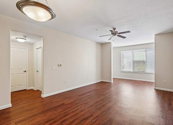 A room with a ceiling fan and wooden floors.