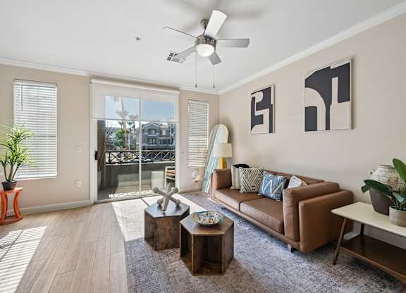 A living room with a brown couch, a coffee table, and a ceiling fan.