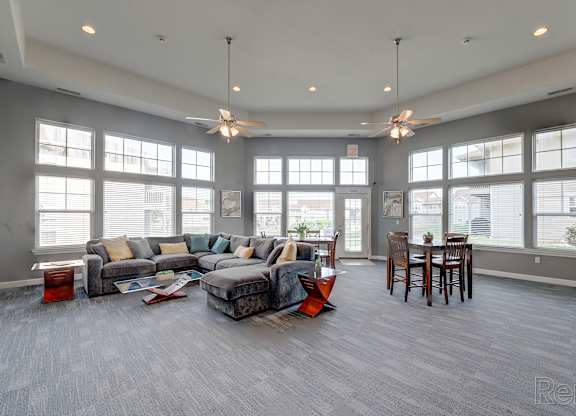 A spacious living room with a grey couch and a grey floor.