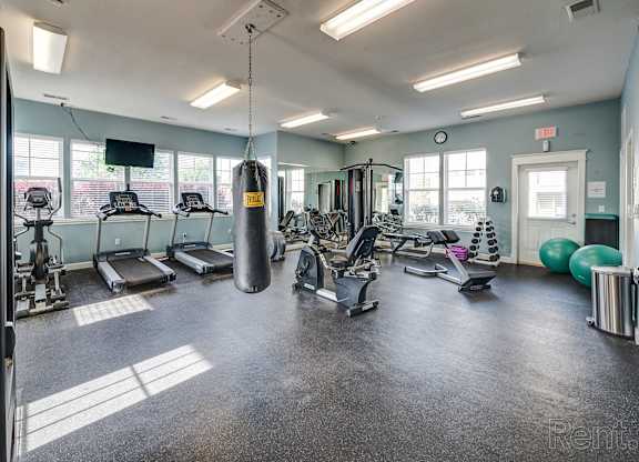 One-Bedroom Apartments in Lawrence, KS - Ironwood Apartments and Townhomes - Fitness Center with Rubber Matting, Cardio Equipment, Dumbbells, Exercise Balls, Punching Bag, Large Mirror, and Windows.