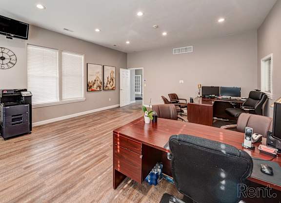 A room with a wooden floor and a desk with a computer on it.