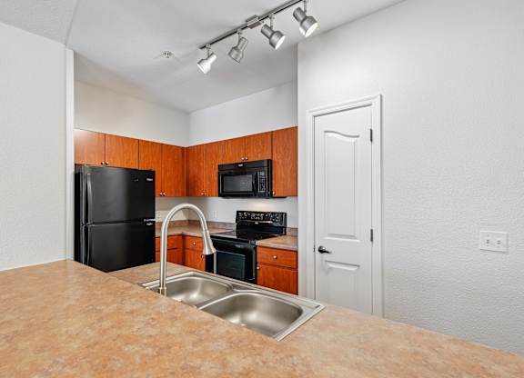 A kitchen with black appliances and wooden cabinets.