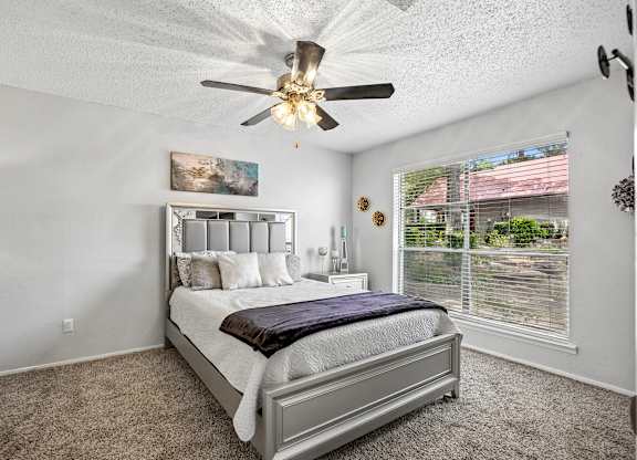 A bedroom with a large bed and a ceiling fan.
