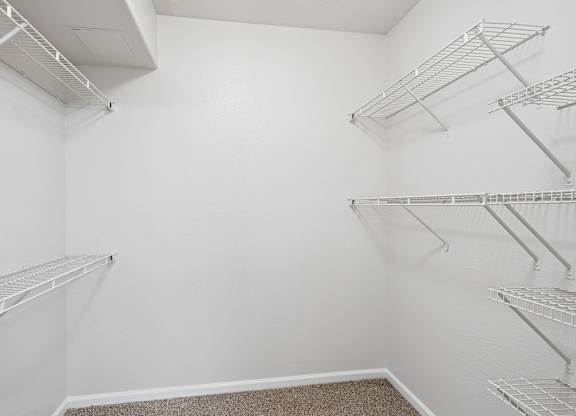 Empty walk-in closet with white shelving.