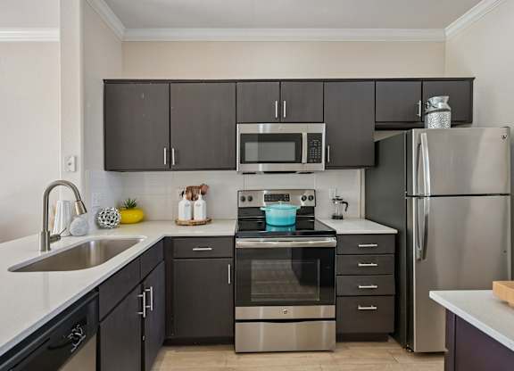 A modern kitchen with dark brown cabinets and stainless steel appliances.