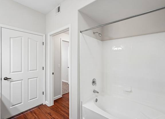 A white bathroom with a tub and a door.