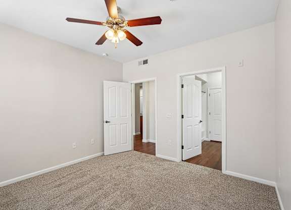 A room with a ceiling fan and carpeted floor.