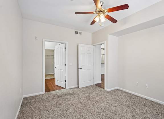 A room with a ceiling fan and carpeted floor.