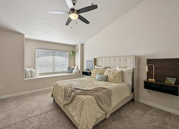 A bedroom with a large bed and a ceiling fan.