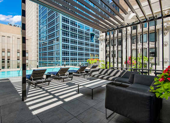A patio with black couches and a pool.
