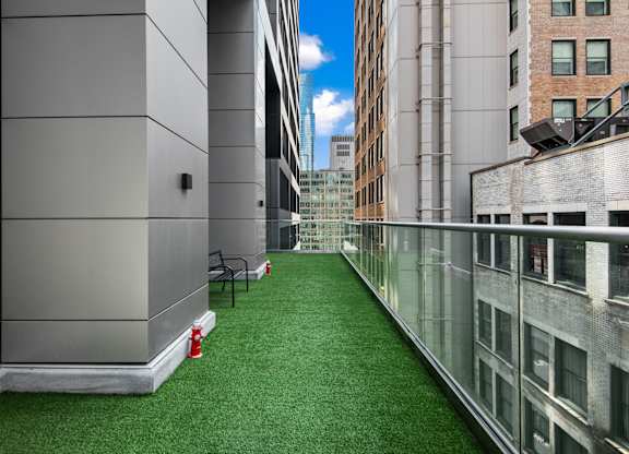 A long, narrow, glass-walled atrium with a green carpet and a red fire extinguisher.