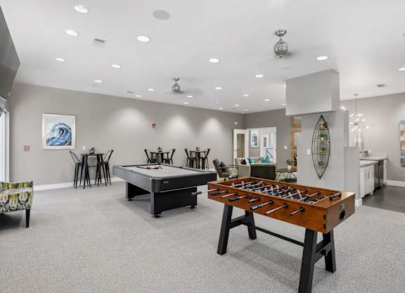 A foosball table is in the middle of a room with a dining table and chairs.
