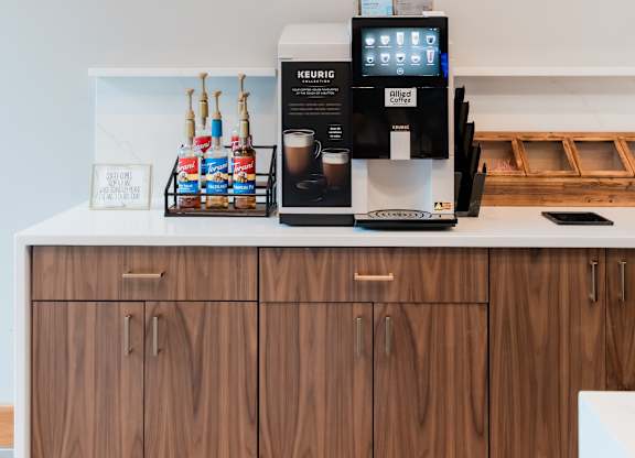 A coffee machine is on a counter with a digital display and a menu.