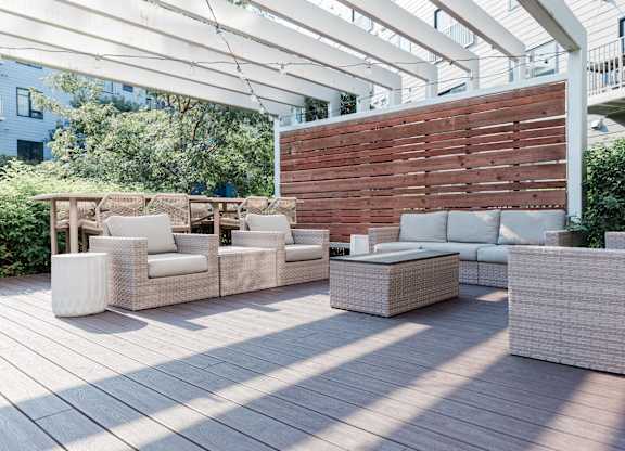 A patio with white furniture and a wooden wall.
