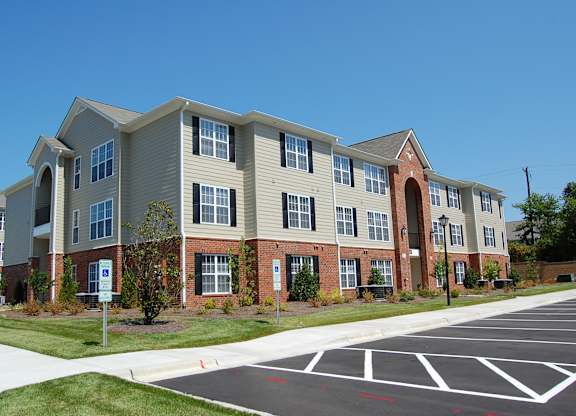 Apartment building with a parking lot in front.