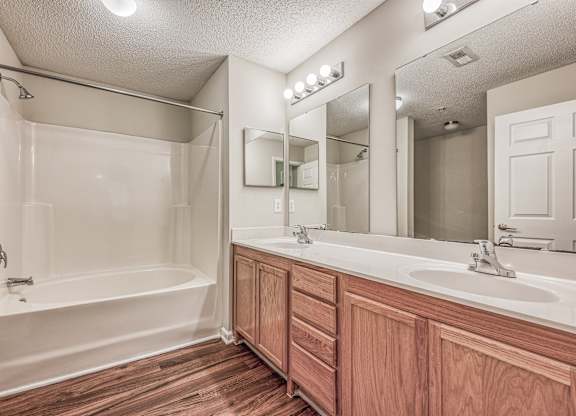 A bathroom with a white tub and wooden cabinets.