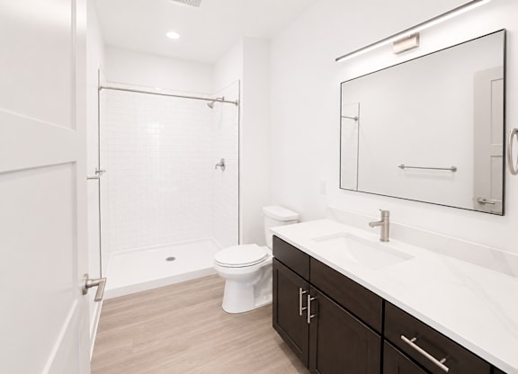 A white toilet sits in a bathroom next to a sink and a mirror.