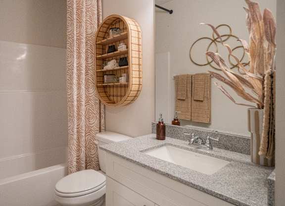 A bathroom with a toilet, sink, and a decorative tree.