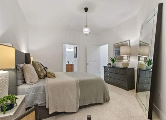 A bedroom with a bed, dresser, and mirror.