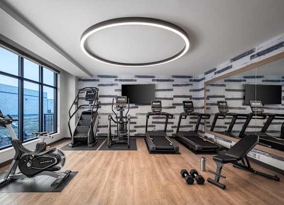 a gym with treadmills and other exercise equipment and a large window