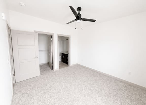 A room with a ceiling fan and carpeted floor.