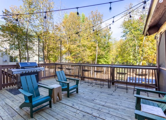 a deck with a picnic table and chairs and a grill at Birchwood Apartment Homes in Maple Grove, MN