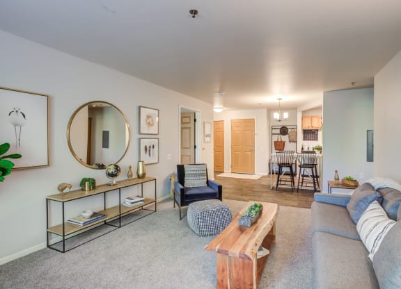 a living room with a couch and a coffee table and a kitchen at Birchwood Apartment Homes in Maple Grove, MN