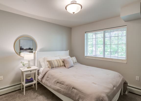 a bedroom with a large bed and a window at Birchwood Apartment Homes in Maple Grove, MN