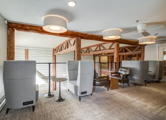 a lounge area with chairs and tables and ceiling lights at Birchwood Apartment Homes in Maple Grove, MN
