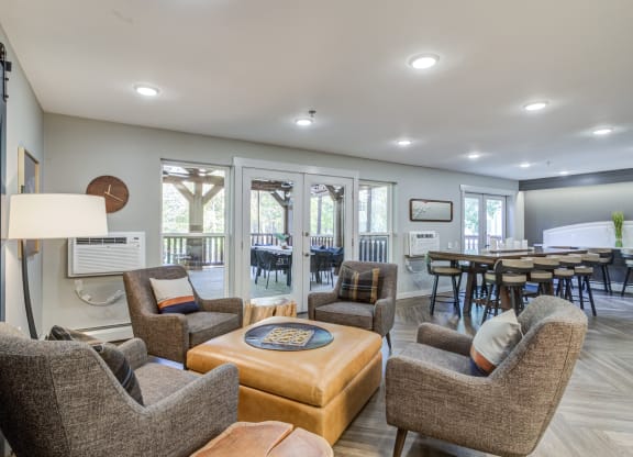a living room with couches and chairs and a dining room with tables at Birchwood Apartment Homes in Maple Grove, MN