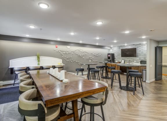 a dining room with tables and chairs and a bar and a television at Birchwood Apartment Homes in Maple Grove, MN