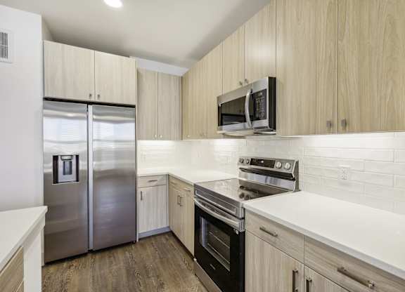 A kitchen with a stainless steel refrigerator, oven, and microwave.