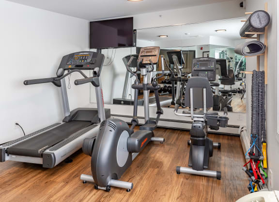 a gym with treadmills and other exercise equipment on a wooden floor