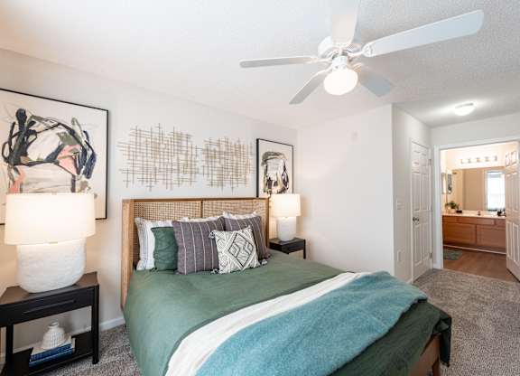 A bedroom with a bed, two lamps, and a painting on the wall.